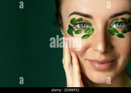 Nahaufnahme`s Gesicht einer jungen Frau mit Buchsbaumblättern. Spa und Wellness Konzept Vorlage Banner für Design. Werbung für kosmetische Produkte Stockfoto